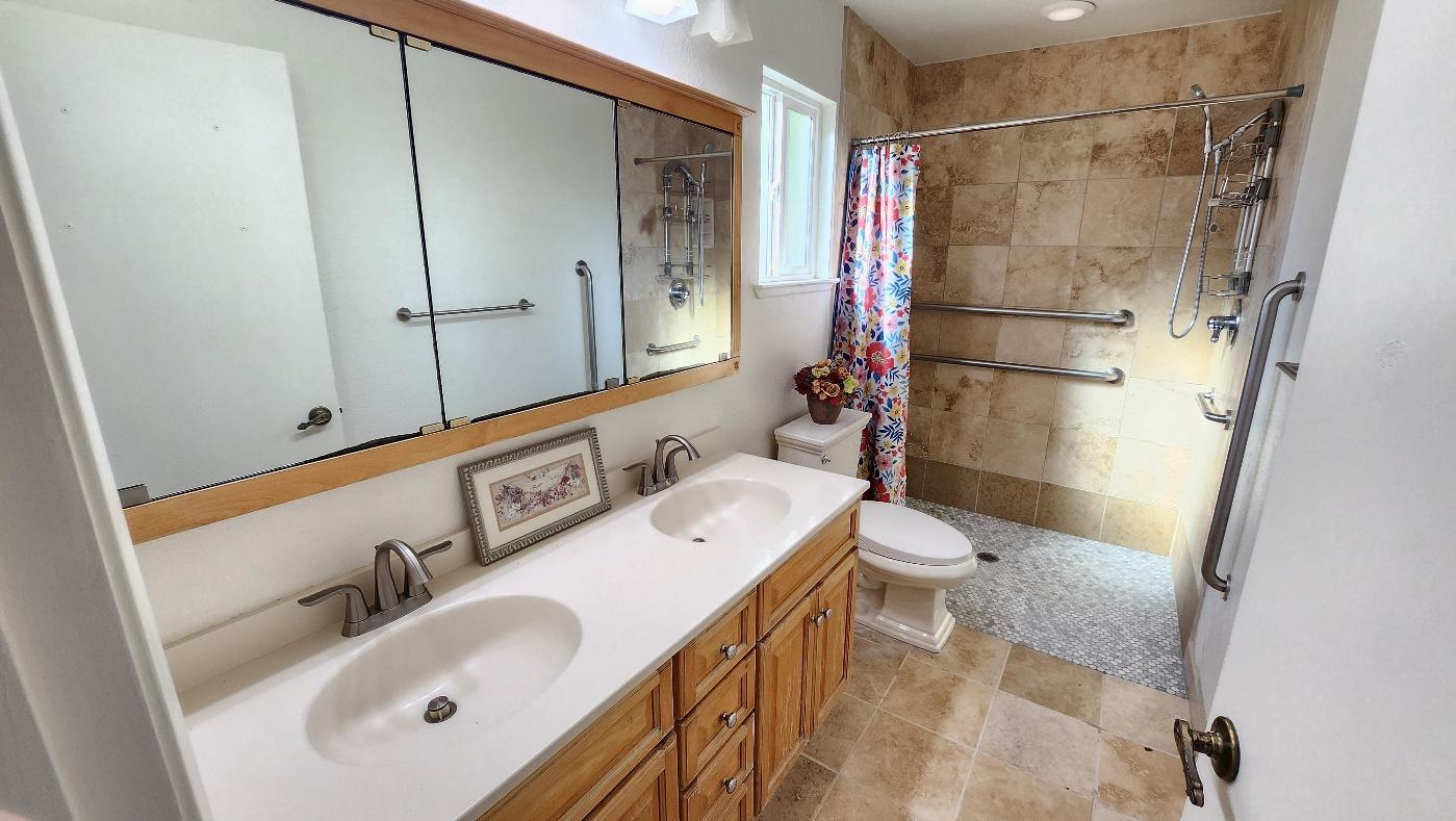 Accessible bathroom with a double vanity and a walk-in shower with grab bars
