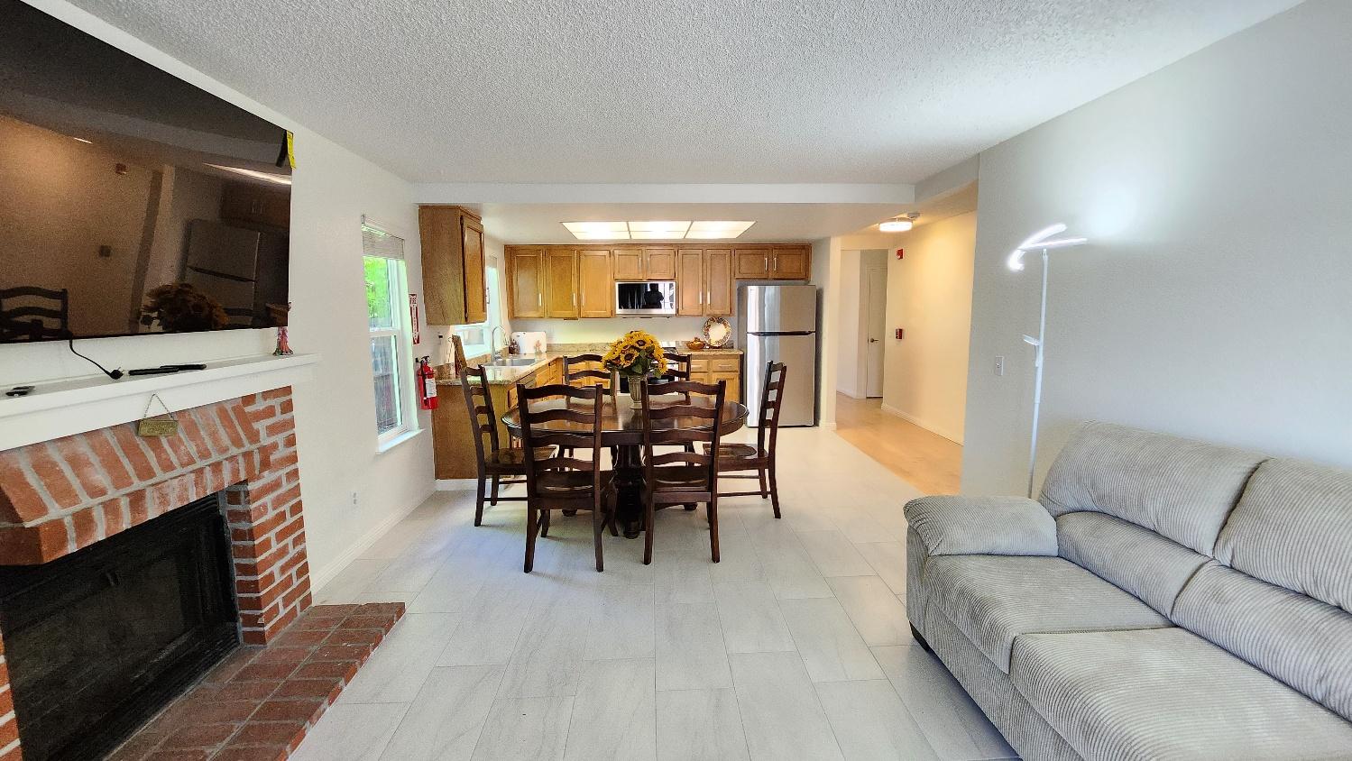 Family gathering space with a brick fireplace, dining table, and view into the kitchen
