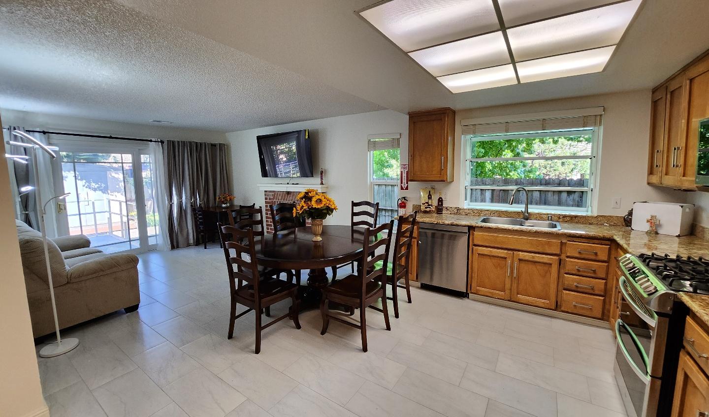 Open-concept kitchen and dining area with wood cabinetry, granite countertops, and a round dining table