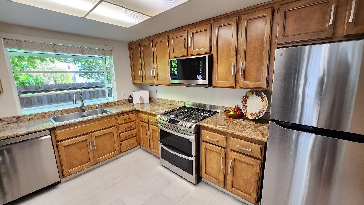 Kitchen with stainless steel appliances, wood cabinetry, and granite countertops