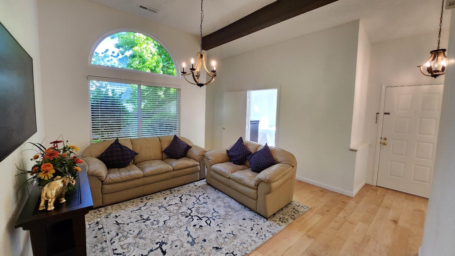 Comfortable living room with tan sofas, a patterned rug, and an arched window